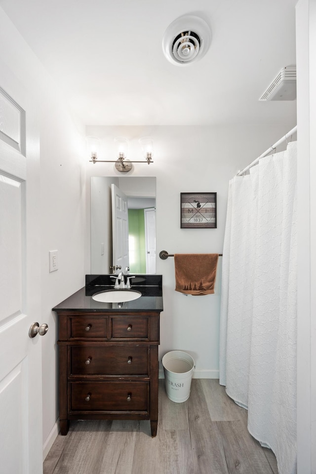 bathroom with visible vents, baseboards, wood finished floors, and vanity