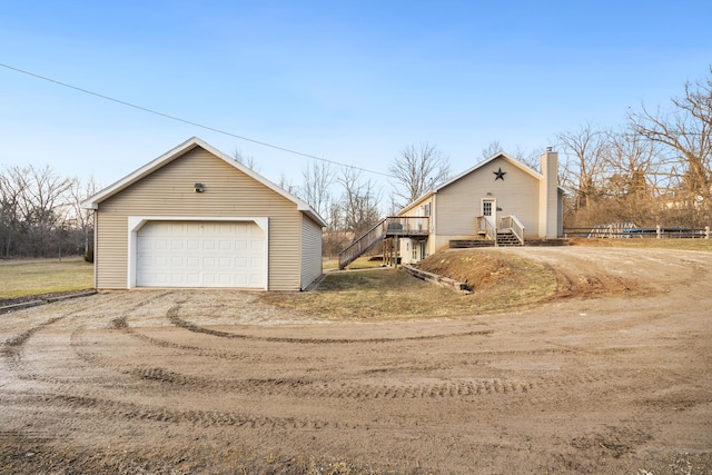 view of front of house featuring a garage, a chimney, and an outdoor structure