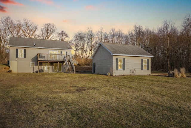 back of property at dusk with stairs, a deck, and a yard