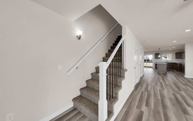 staircase featuring recessed lighting, wood finished floors, and baseboards