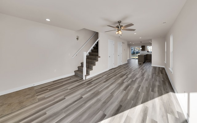 unfurnished living room with recessed lighting, wood finished floors, ceiling fan, and stairs