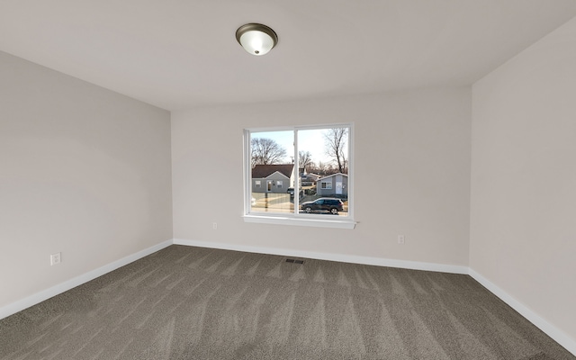 unfurnished room with visible vents, baseboards, and dark colored carpet