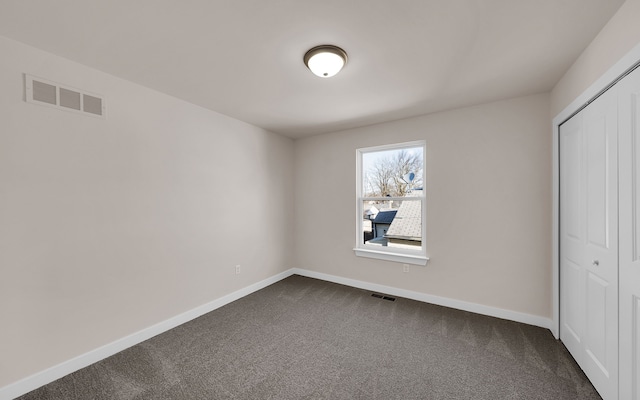 unfurnished bedroom featuring a closet, baseboards, visible vents, and dark carpet