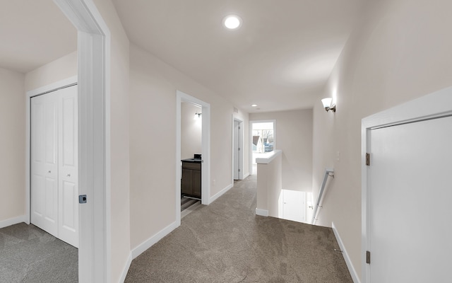 hallway featuring carpet, an upstairs landing, and baseboards