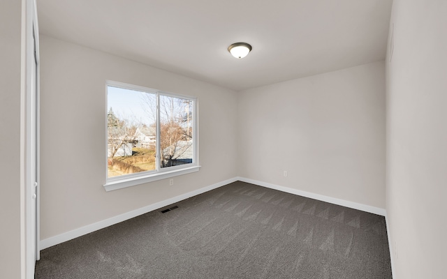 spare room with visible vents, baseboards, and dark carpet