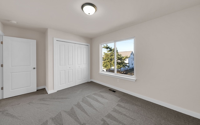 unfurnished bedroom with carpet, baseboards, visible vents, and a closet