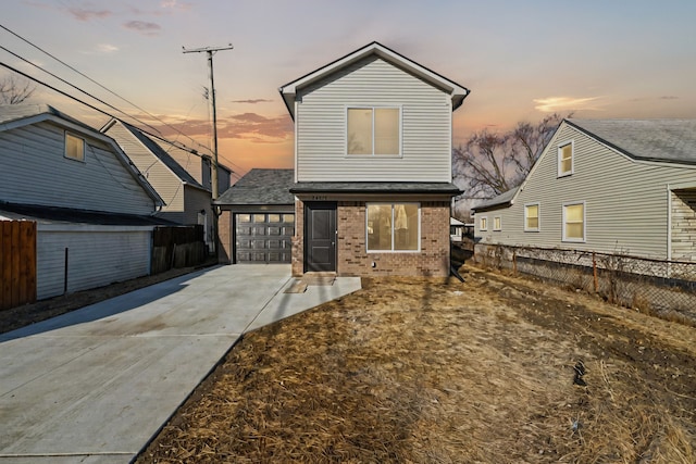 traditional home with a garage, fence, brick siding, and driveway