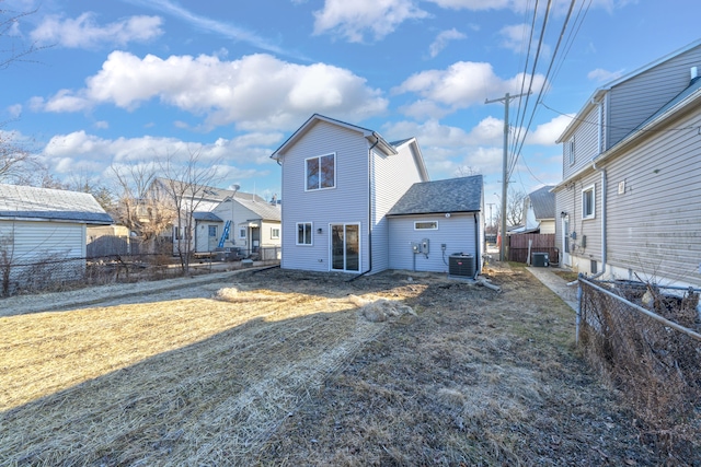 back of property featuring fence, a lawn, and central AC