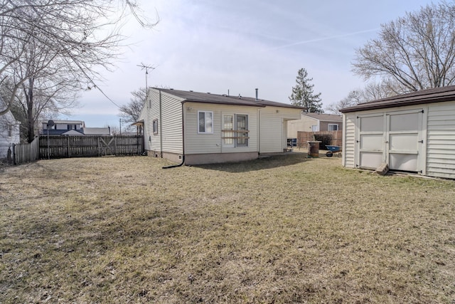 rear view of house with an outbuilding, a shed, a lawn, and fence