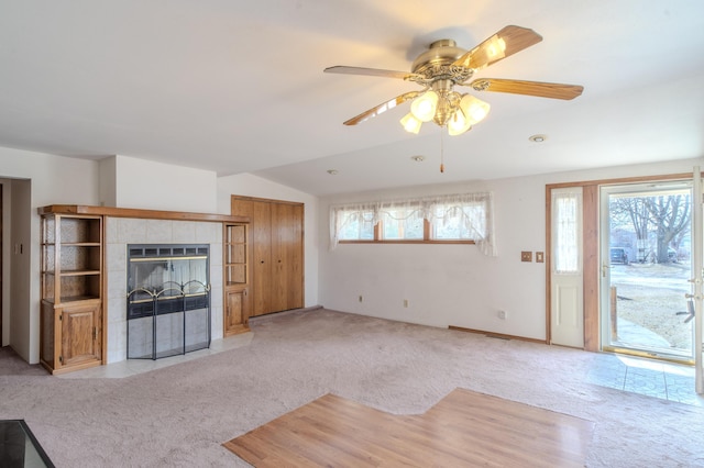 unfurnished living room featuring light carpet, lofted ceiling, a healthy amount of sunlight, and a fireplace