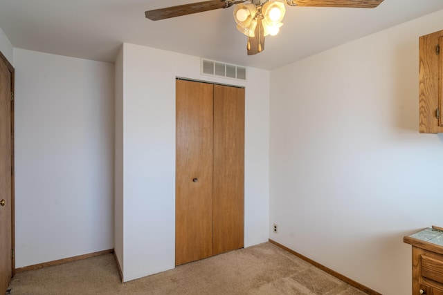 unfurnished bedroom with visible vents, baseboards, ceiling fan, a closet, and light colored carpet