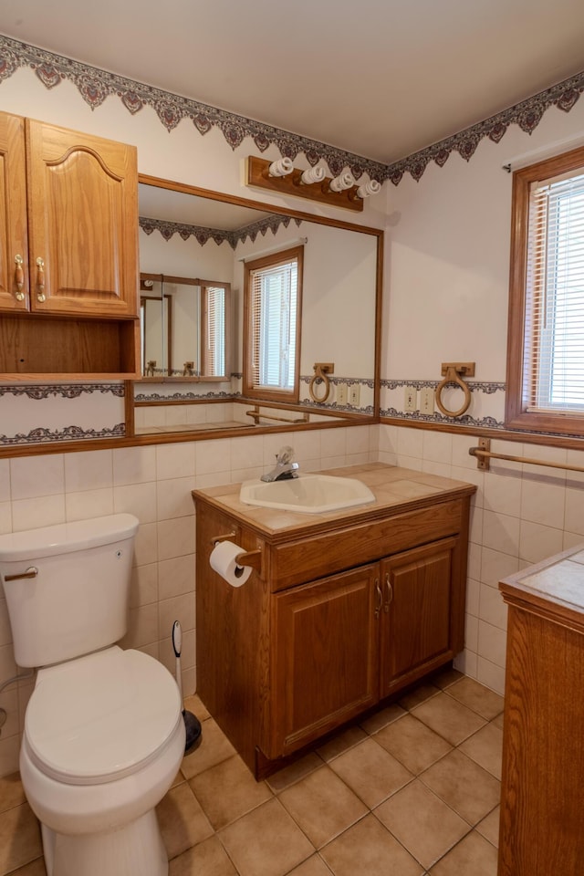 bathroom with tile patterned floors, toilet, tile walls, and vanity