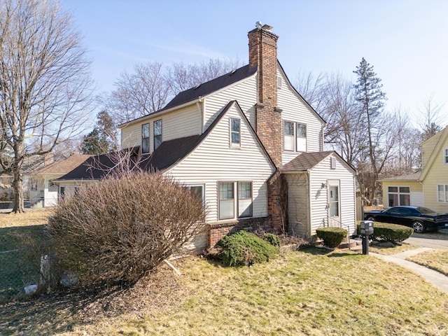 view of property exterior with a lawn, brick siding, and a chimney