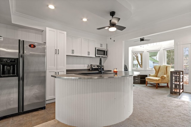 kitchen with a center island with sink, ornamental molding, appliances with stainless steel finishes, white cabinets, and a sink