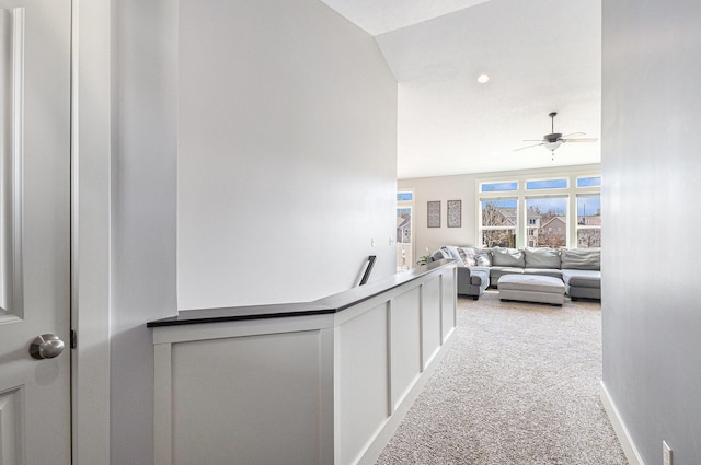 hall featuring baseboards and light carpet