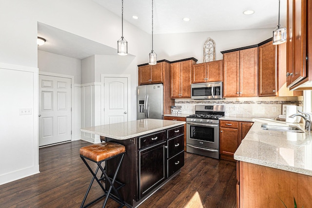 kitchen with brown cabinetry, dark wood-style flooring, appliances with stainless steel finishes, and a sink