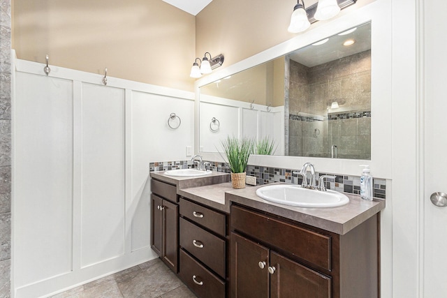 full bathroom with double vanity, tasteful backsplash, a stall shower, and a sink