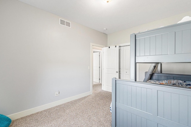 bedroom with carpet flooring, visible vents, baseboards, and a closet