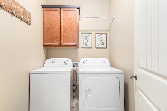 clothes washing area with washing machine and clothes dryer and cabinet space