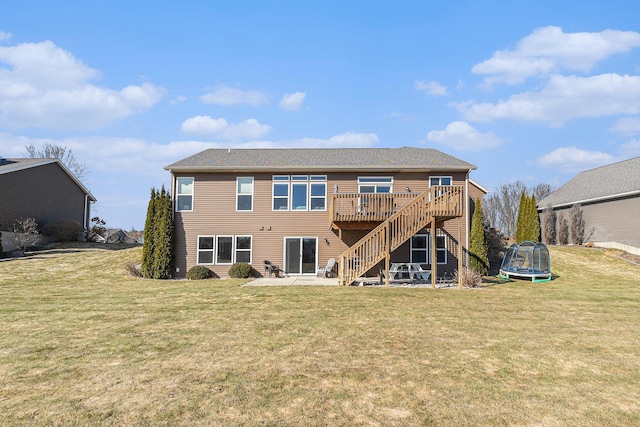 rear view of house with a lawn, a deck, a trampoline, stairs, and a patio area