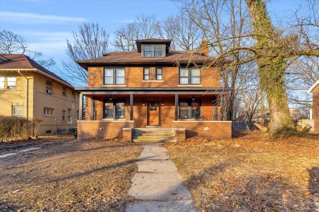 american foursquare style home featuring brick siding, covered porch, and a chimney