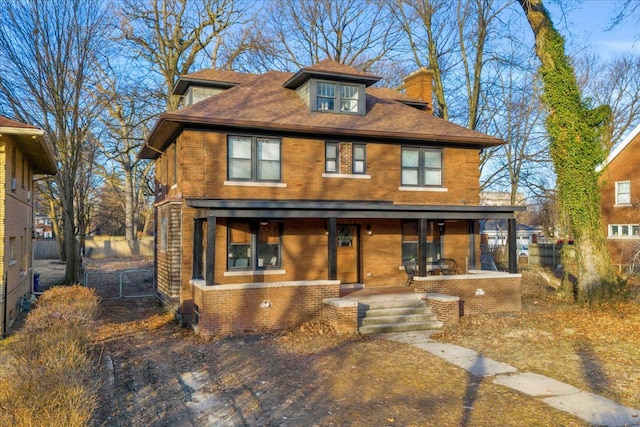 traditional style home with brick siding, a porch, and a chimney