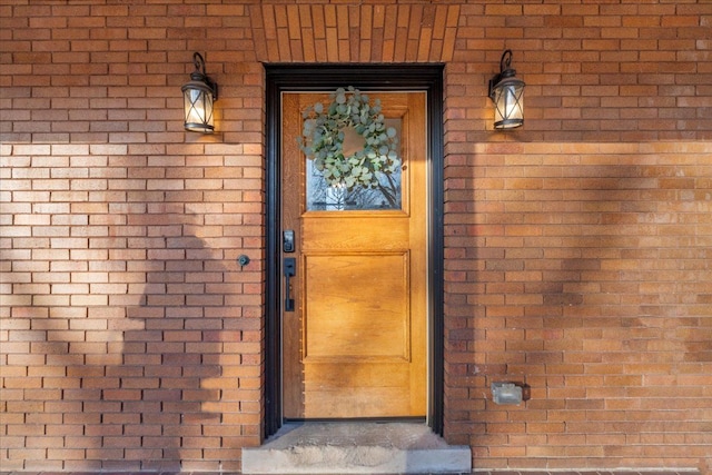 doorway to property with brick siding and roof with shingles