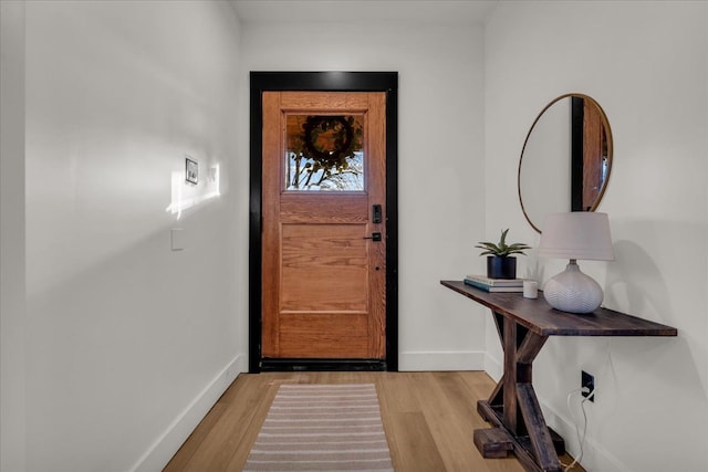 doorway with baseboards and light wood-style flooring