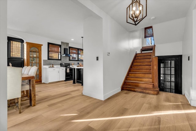 stairway with wood finished floors, baseboards, and a chandelier