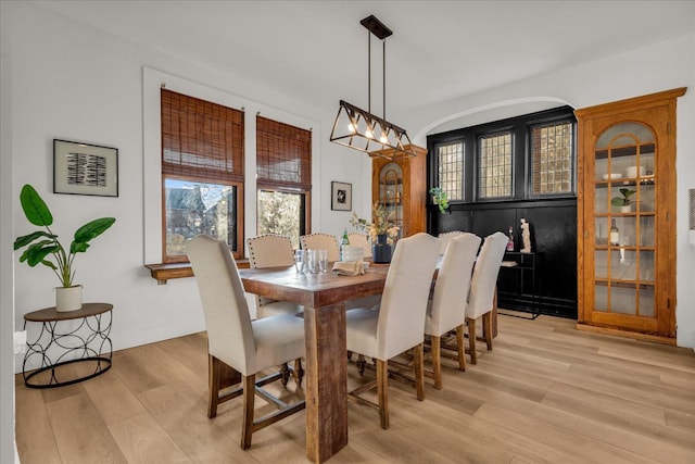 dining area featuring a notable chandelier, baseboards, and light wood-style floors