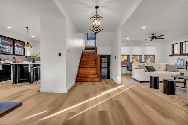 stairs with recessed lighting, baseboards, wood finished floors, and ceiling fan with notable chandelier