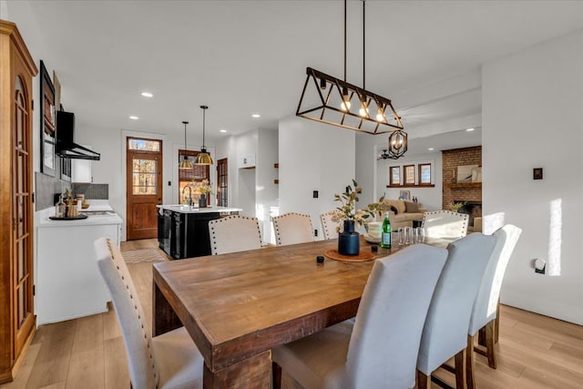 dining space featuring recessed lighting, a brick fireplace, and light wood-style flooring