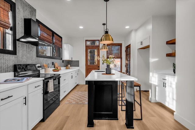 kitchen featuring light wood-style flooring, backsplash, black range with electric stovetop, and wall chimney range hood