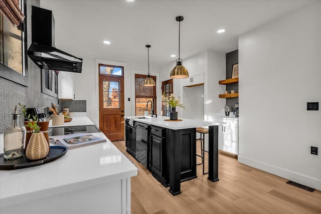 kitchen with light countertops, stove, black dishwasher, wall chimney exhaust hood, and dark cabinets