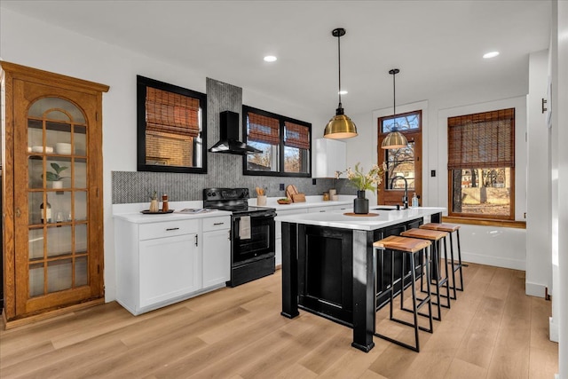 kitchen featuring light countertops, black electric range oven, backsplash, and a sink