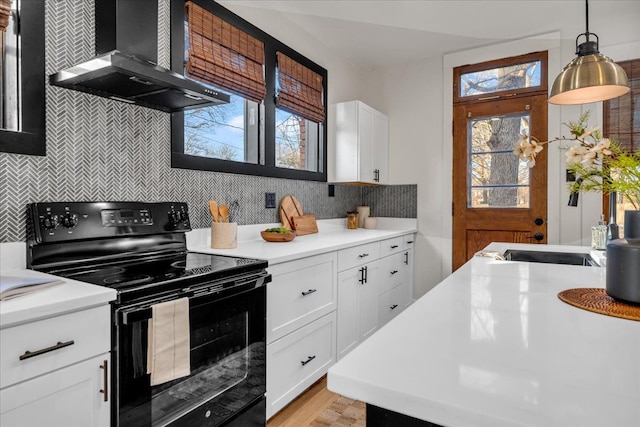 kitchen featuring electric range, light countertops, wall chimney exhaust hood, and decorative backsplash