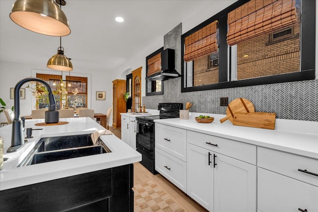 kitchen featuring a sink, ventilation hood, black / electric stove, light countertops, and decorative backsplash