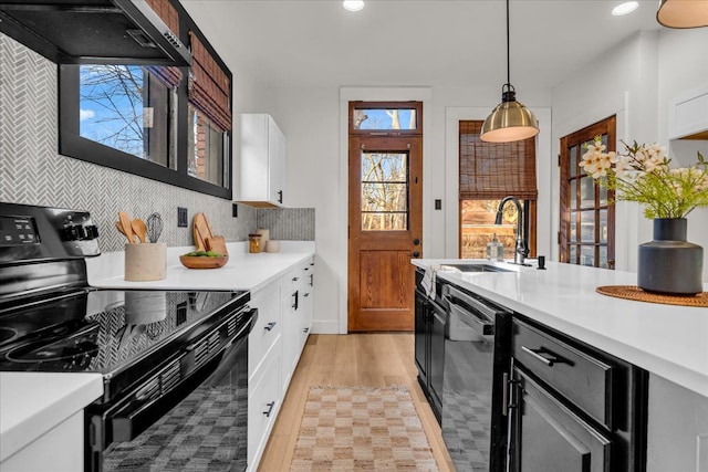 kitchen featuring black appliances, range hood, and light countertops