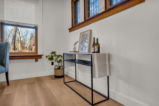 sitting room with a wealth of natural light, a towering ceiling, baseboards, and wood finished floors