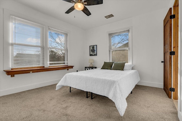 carpeted bedroom featuring baseboards, multiple windows, and ceiling fan