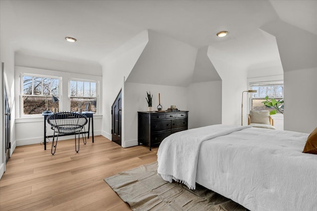 bedroom featuring baseboards, light wood-style floors, and vaulted ceiling