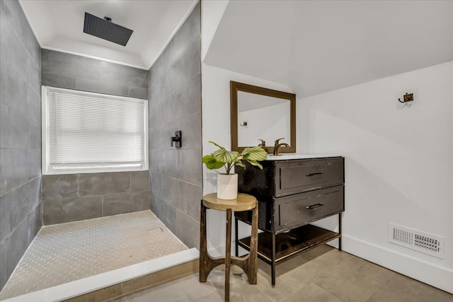 full bath with a tile shower, visible vents, and vanity