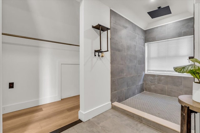 full bathroom with wood finished floors, baseboards, and tiled shower