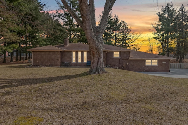 view of front of property featuring a front lawn, brick siding, and a chimney