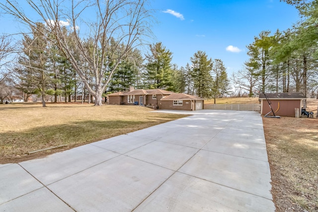 exterior space featuring fence, a shed, a front yard, a garage, and an outdoor structure