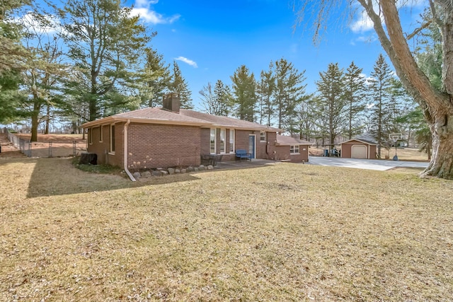 rear view of property featuring brick siding, a lawn, a chimney, and an outbuilding