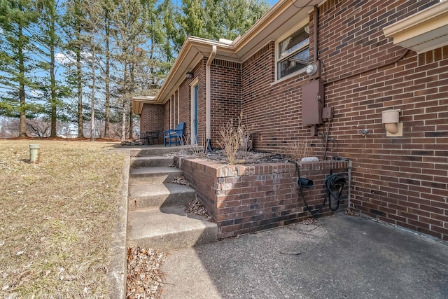 view of side of property featuring brick siding and a patio