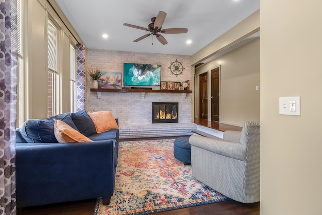 living area featuring wood finished floors, a brick fireplace, recessed lighting, and a ceiling fan