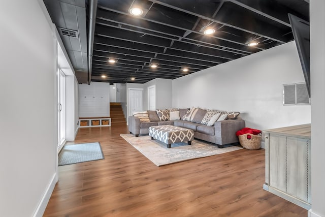 living area with visible vents, stairway, and wood finished floors