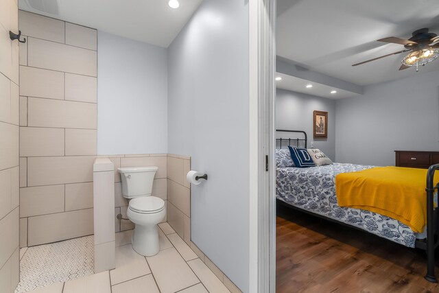 ensuite bathroom featuring toilet, a ceiling fan, ensuite bath, recessed lighting, and tile walls